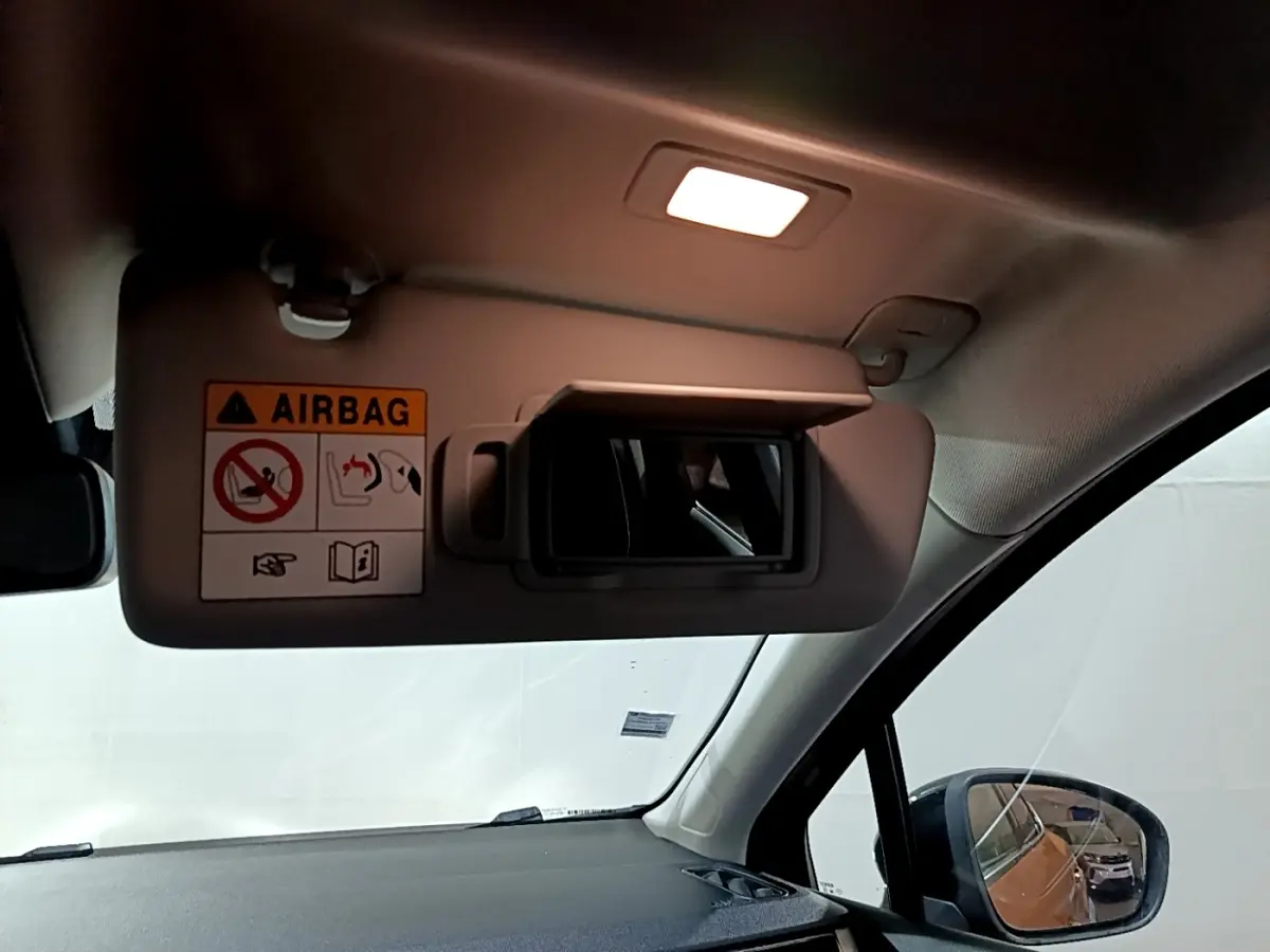 Détail du pare-soleil côté conducteur avec miroir et avertissement airbag, intérieur clair du Renault Captur jaune.