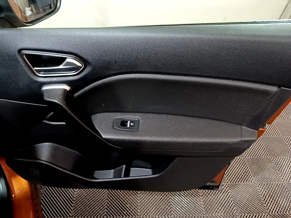 Vue intérieure du panneau de porte avant gauche noir du Renault Captur jaune 2020 avec poignée argentée et bouton de vitre électrique.