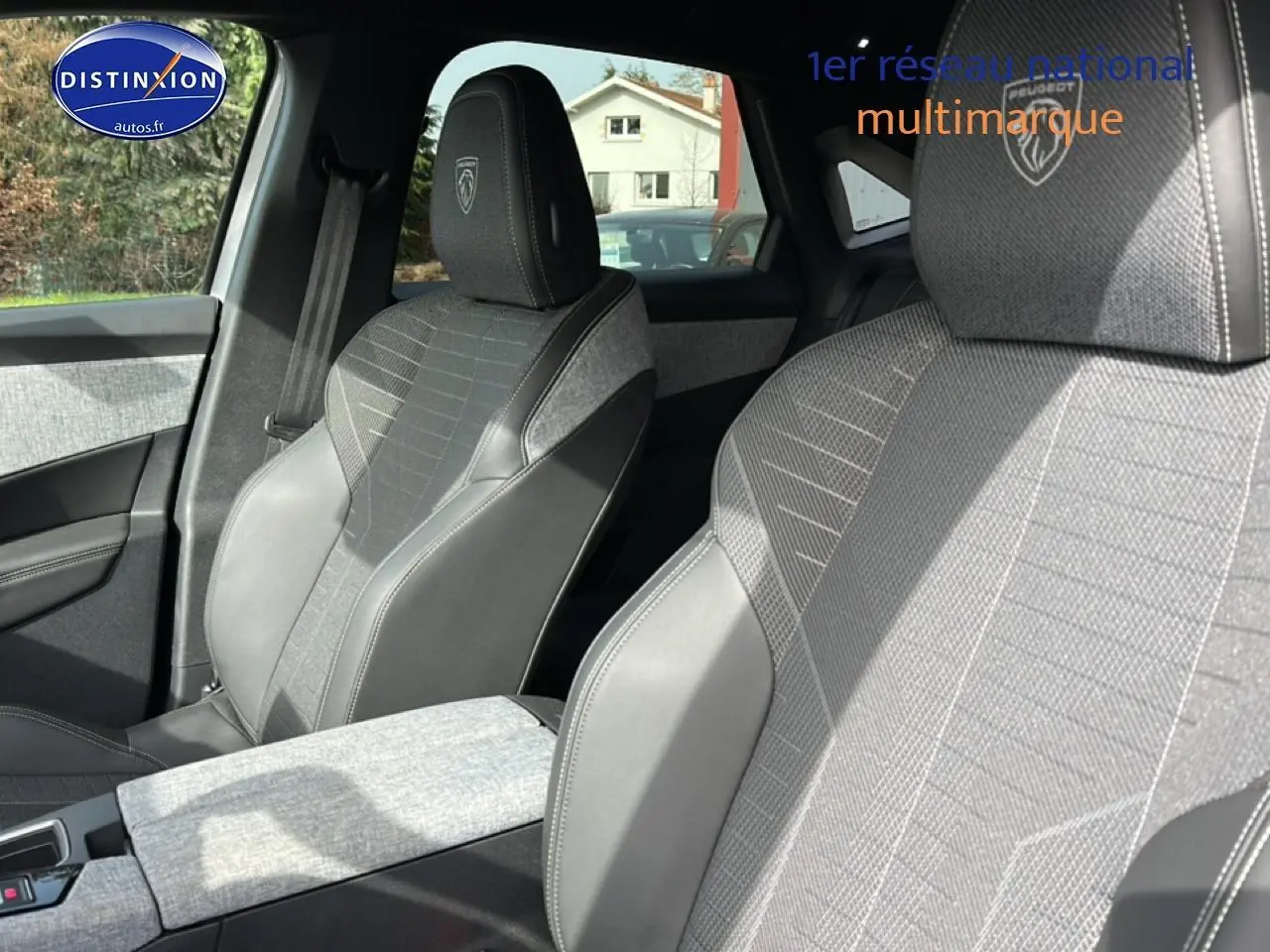 Gros plan sur les sièges avant gris et noirs du Peugeot 3008 1.2 Hybrid 145 GT, avec logo Peugeot brodé sur les appuie-tête.