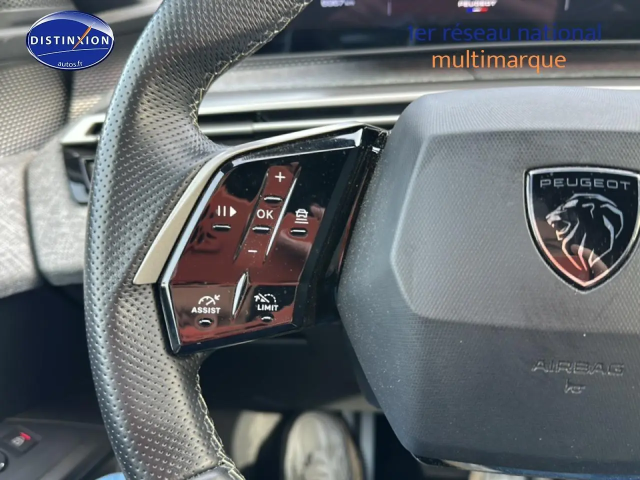 Gros plan sur le volant cuir perforé gris du Peugeot 3008 2025 avec commandes multifonctions et logo lion central.