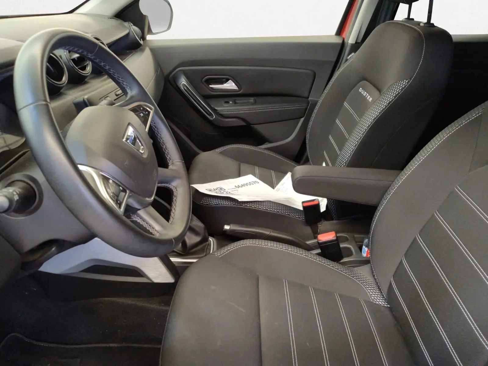 Vue intérieure côté conducteur du Dacia Duster 2021, sièges noirs avec logo Duster et volant multifonction.