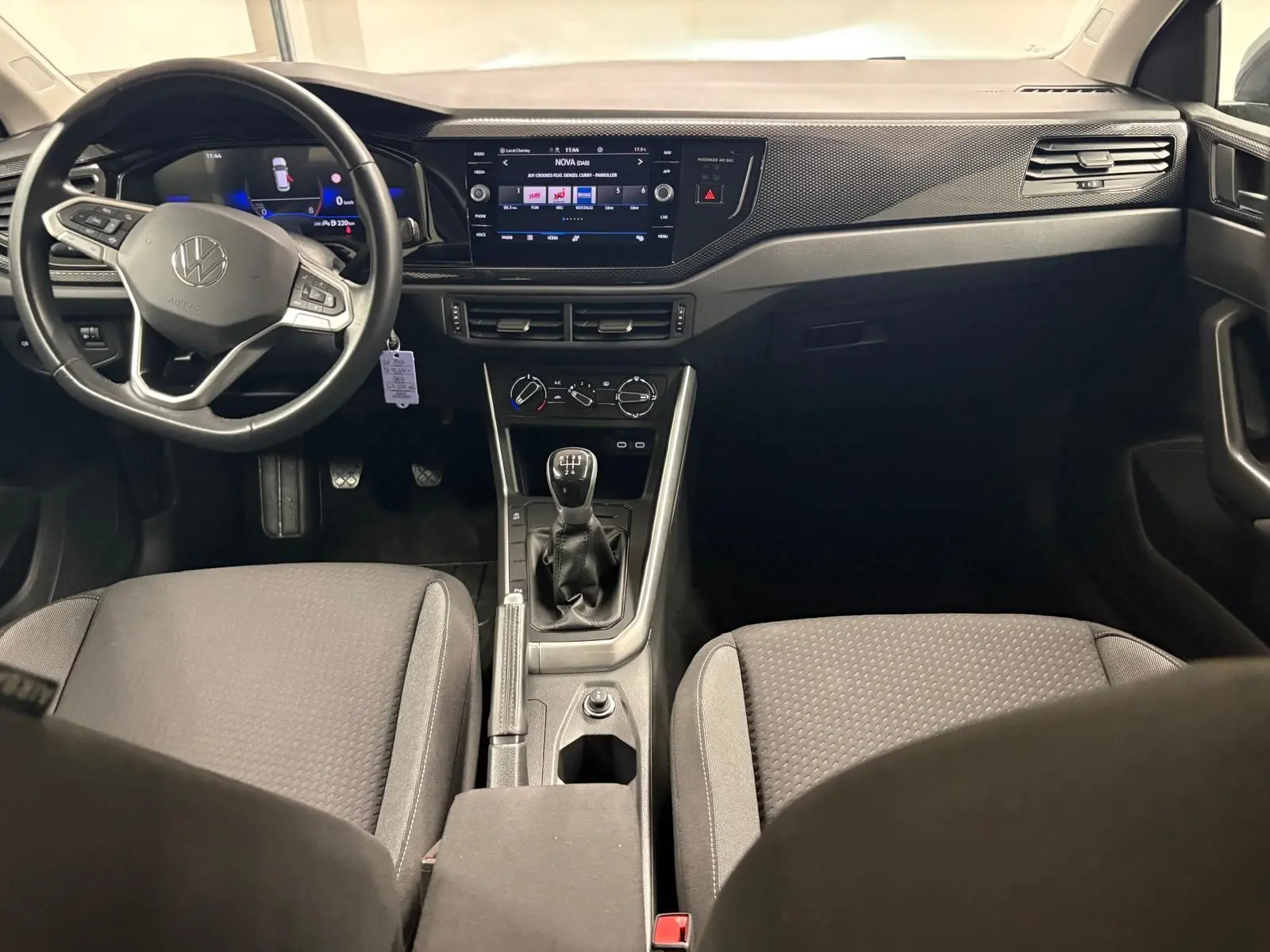 Vue intérieure avant de la Volkswagen Polo 2024 gris cendre, avec tableau de bord numérique et boîte manuelle visible.