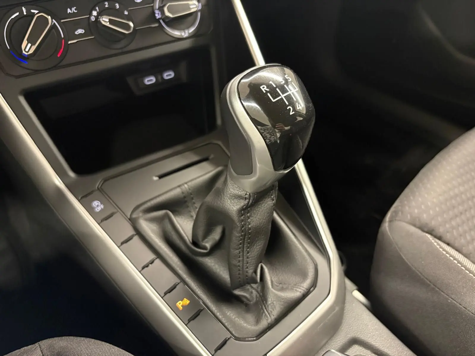 Le levier de vitesses manuel noir de la Volkswagen Polo 2024, avec commandes de climatisation en arrière-plan.