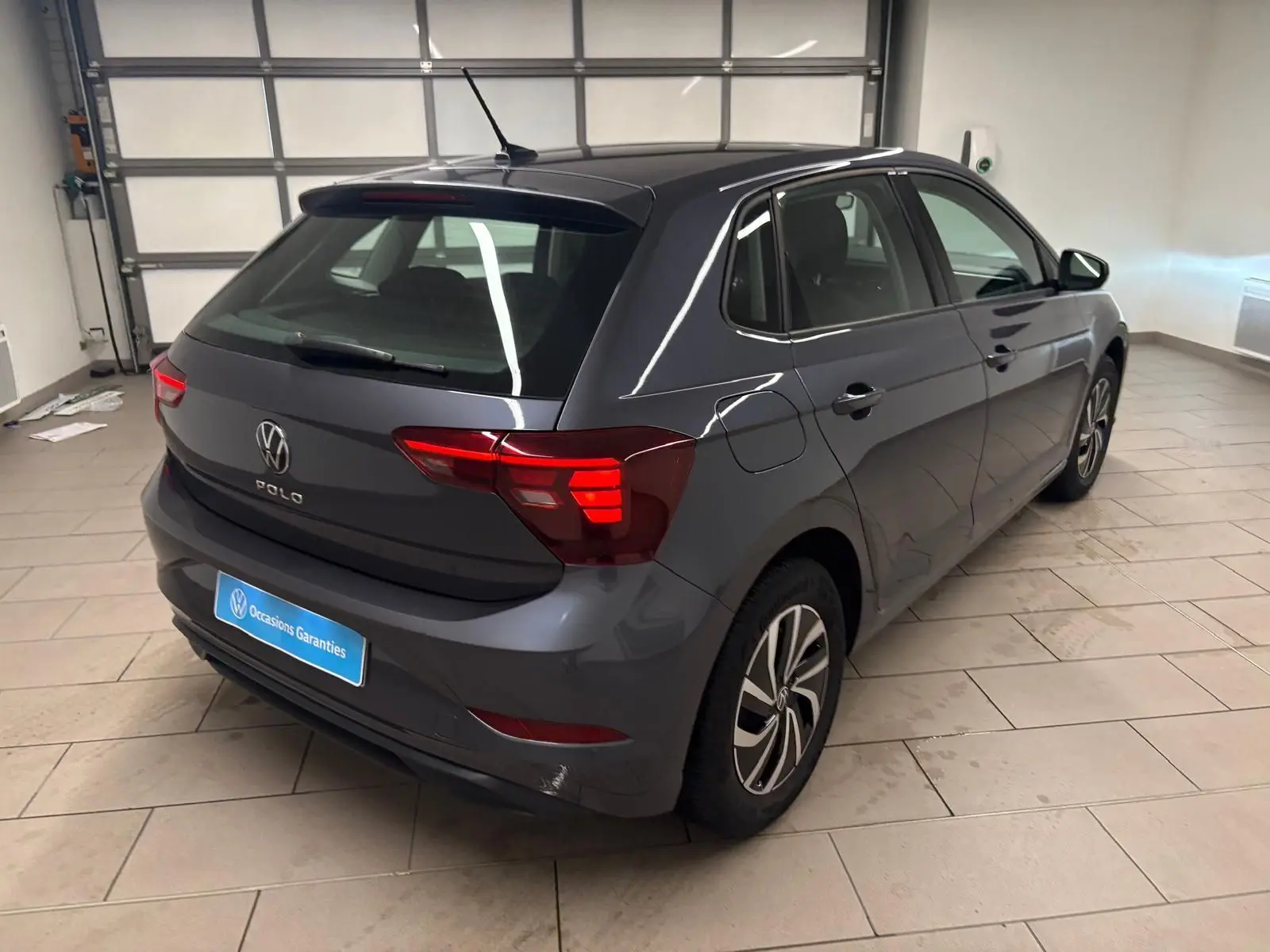 Volkswagen Polo gris cendre vue 3/4 arrière droit en intérieur, avec feux arrière LED et jantes alliage.