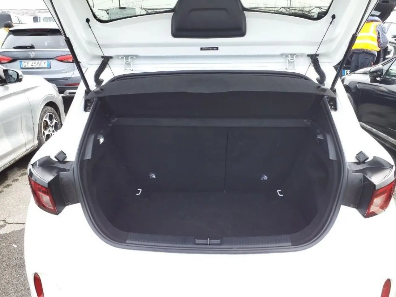 Coffre ouvert vu de l'arrière d'une MG3 1.5 Hybrid+ 195 Luxury blanc Dover, intérieur noir spacieux et vide.