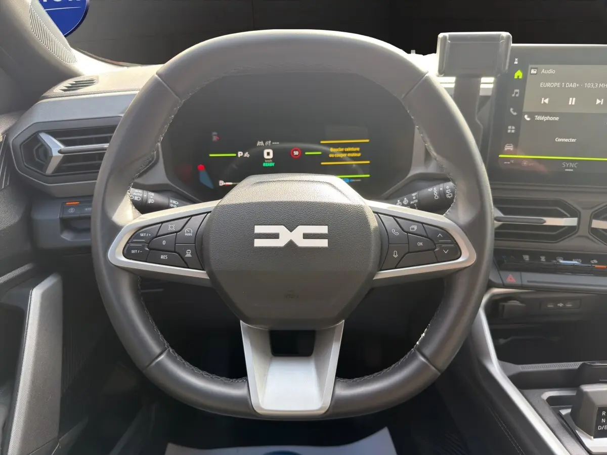 Vue rapprochée du volant cuir synthétique noir du Dacia Bigster 2025 avec tableau de bord numérique et écran tactile central.