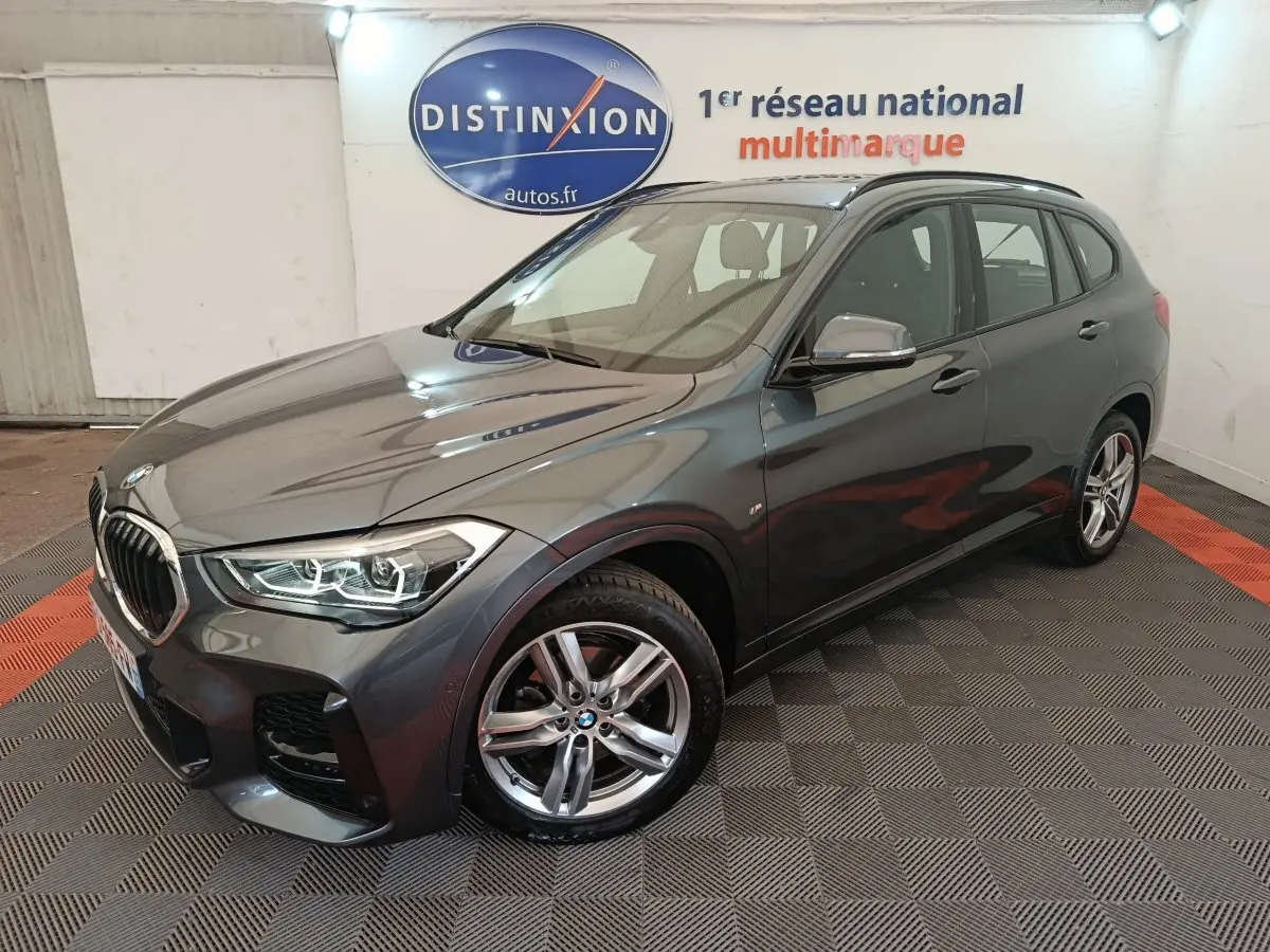 BMW X1 sDrive18i M Sport gris métallisé vue 3/4 avant droit en intérieur showroom avec jantes alliage cinq branches