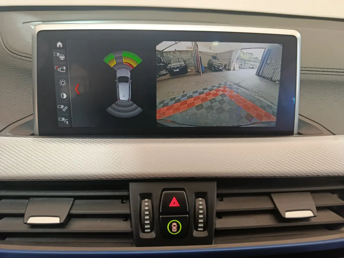 Écran tactile central de la BMW X1 sDrive18i 2019 affichant la caméra de recul et l'aide au stationnement.