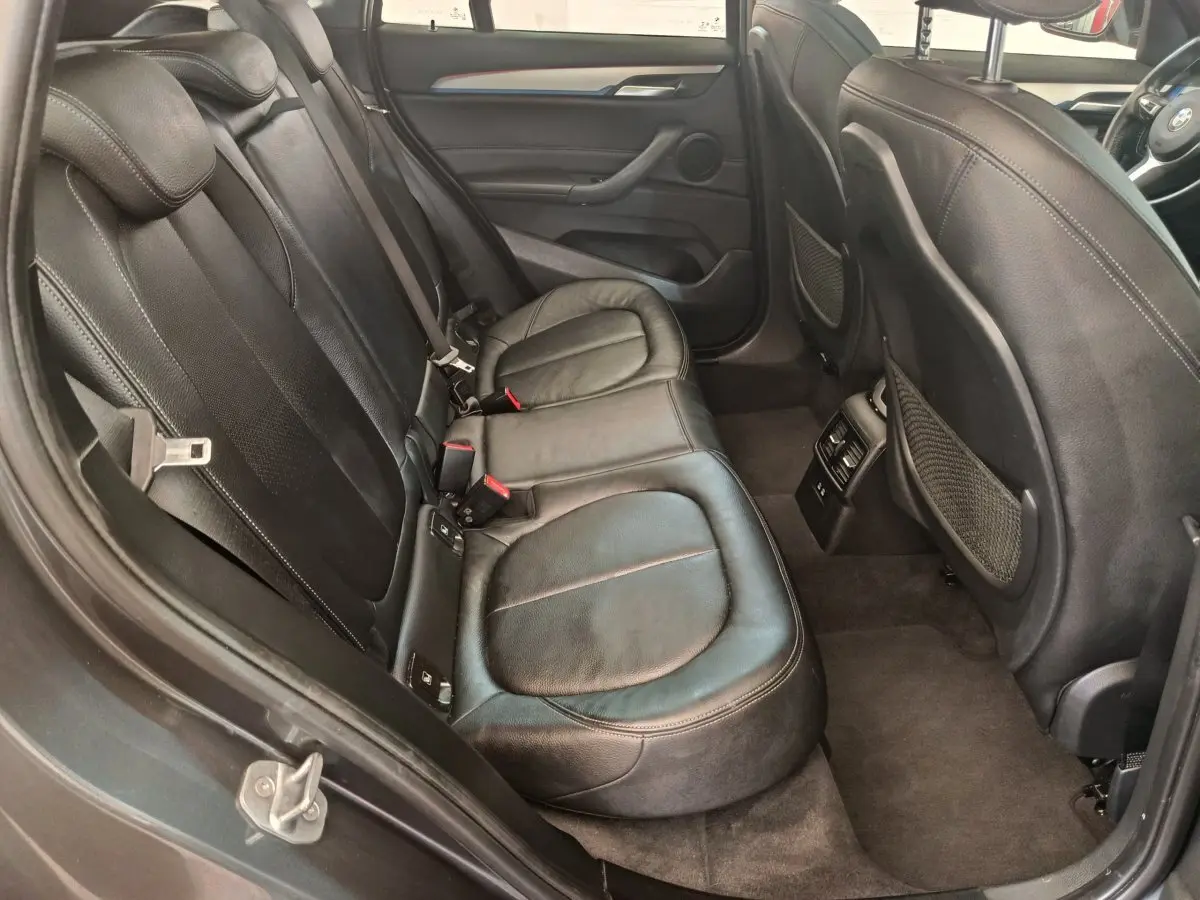 Vue intérieure arrière côté gauche du BMW X1 sDrive18i M Sport 2019 avec sièges cuir noirs et finitions soignées