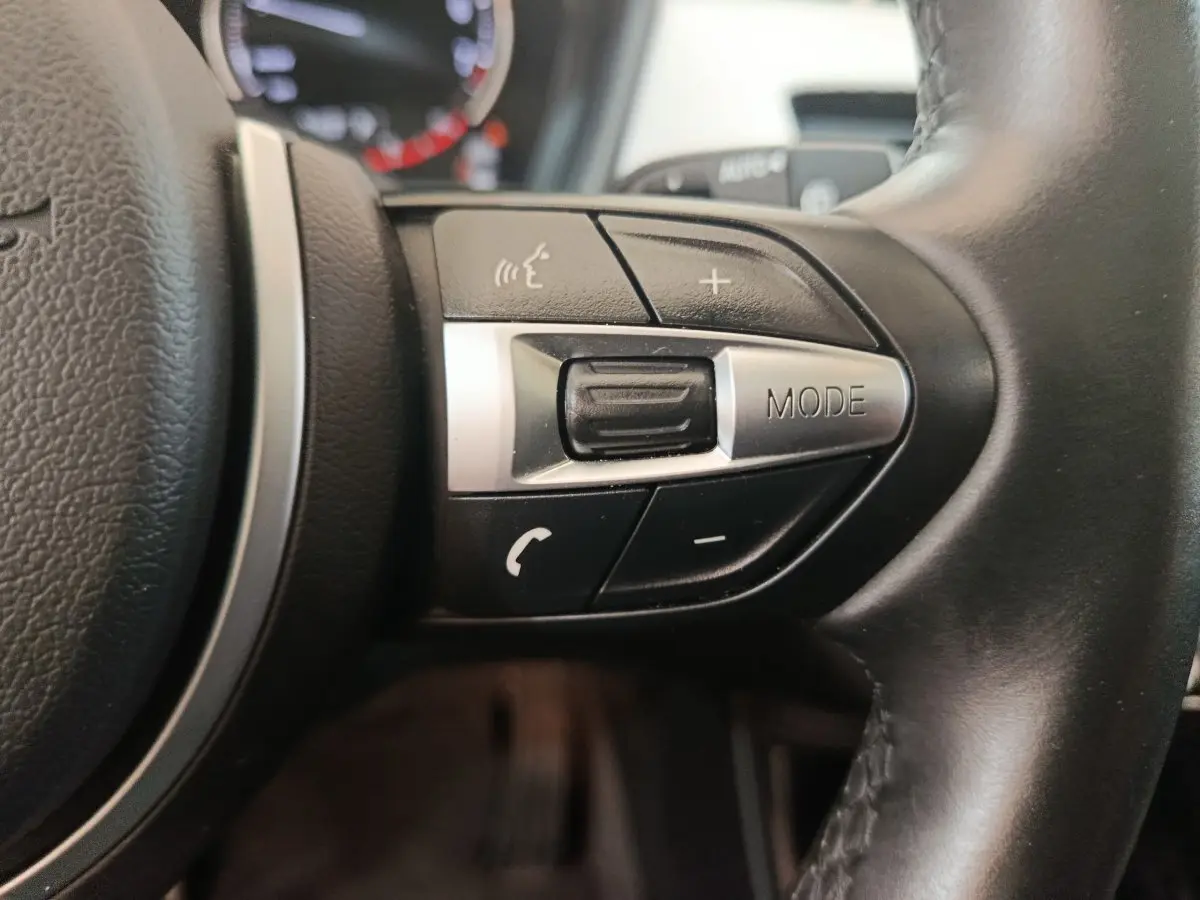 Gros plan sur les commandes du volant côté gauche en cuir noir du BMW X1 sDrive18i M Sport 2019.