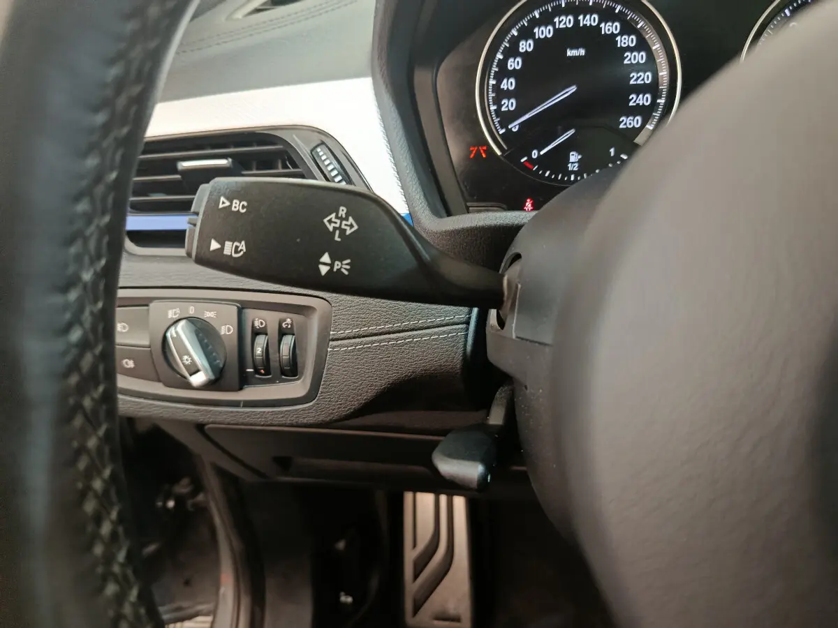 Gros plan sur la commande de clignotant et le tableau de bord noir du BMW X1 sDrive18i M Sport 2019.