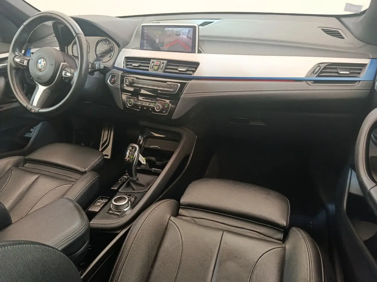 Intérieur noir de BMW X1 sDrive18i M Sport 2019, vue côté conducteur avec tableau de bord et écran tactile central.