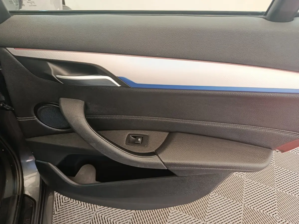 Panneau de porte côté gauche noir avec insert blanc et bleu, poignée argentée, haut-parleur rond visible.