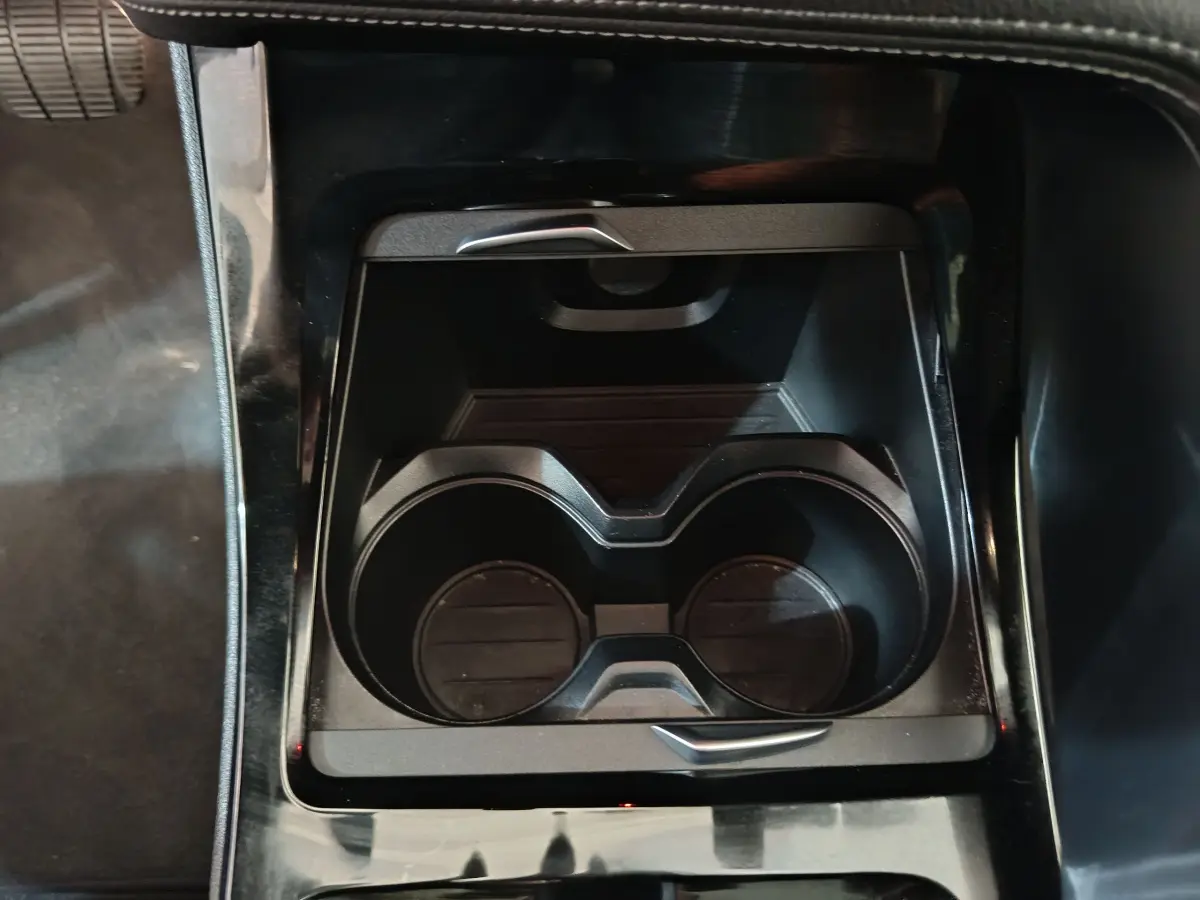 Gros plan sur les porte-gobelets centraux noirs du BMW X1 sDrive18i M Sport DKG7, intérieur sombre.