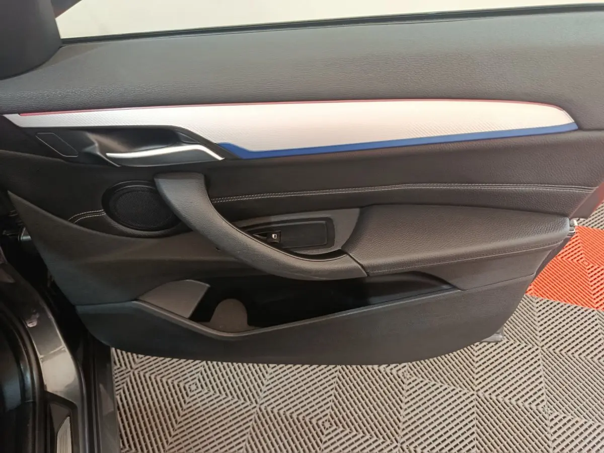 Vue latérale du panneau de porte avant gauche noir avec insert blanc et bleu sur BMW X1 sDrive18i M Sport 2019.
