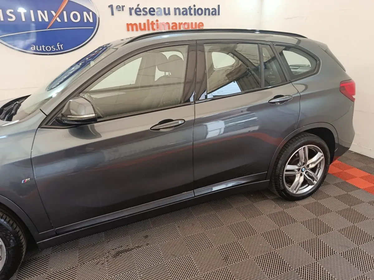 BMW X1 sDrive18i M Sport gris foncé vue de profil côté gauche avec jantes alliage et logo M Sport sur aile avant