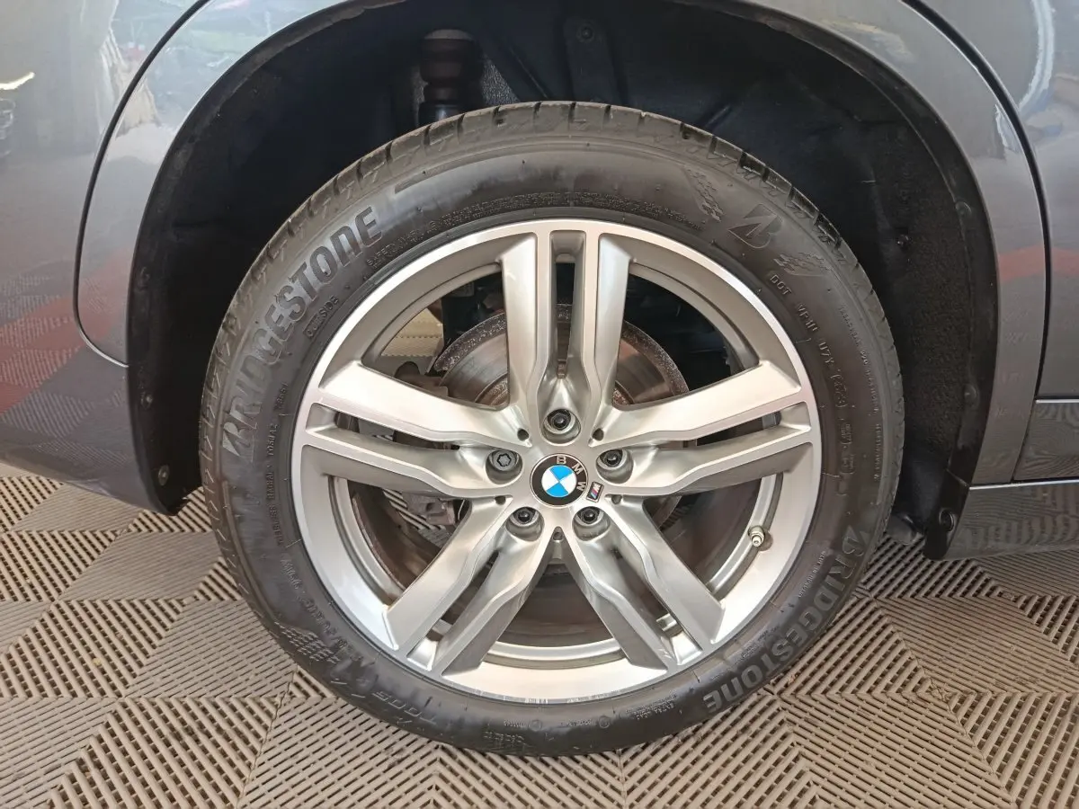 Gros plan sur la roue avant gauche du BMW X1 sDrive18i M Sport 2019 avec jante alliage argentée et pneu Bridgestone.