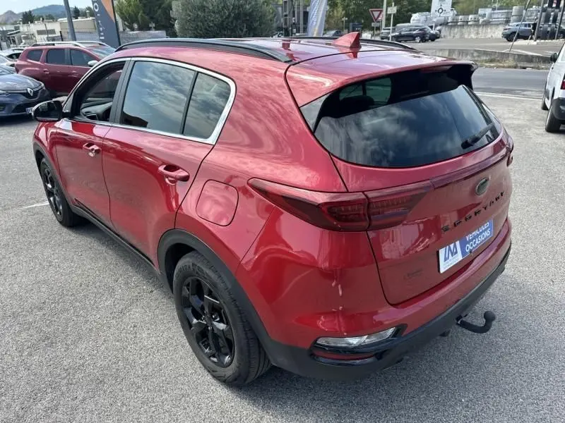 Vue 3/4 arrière droite du KIA SPORTAGE rouge métallisé avec jantes noires et toit panoramique, modèle 2021 Black Edition.