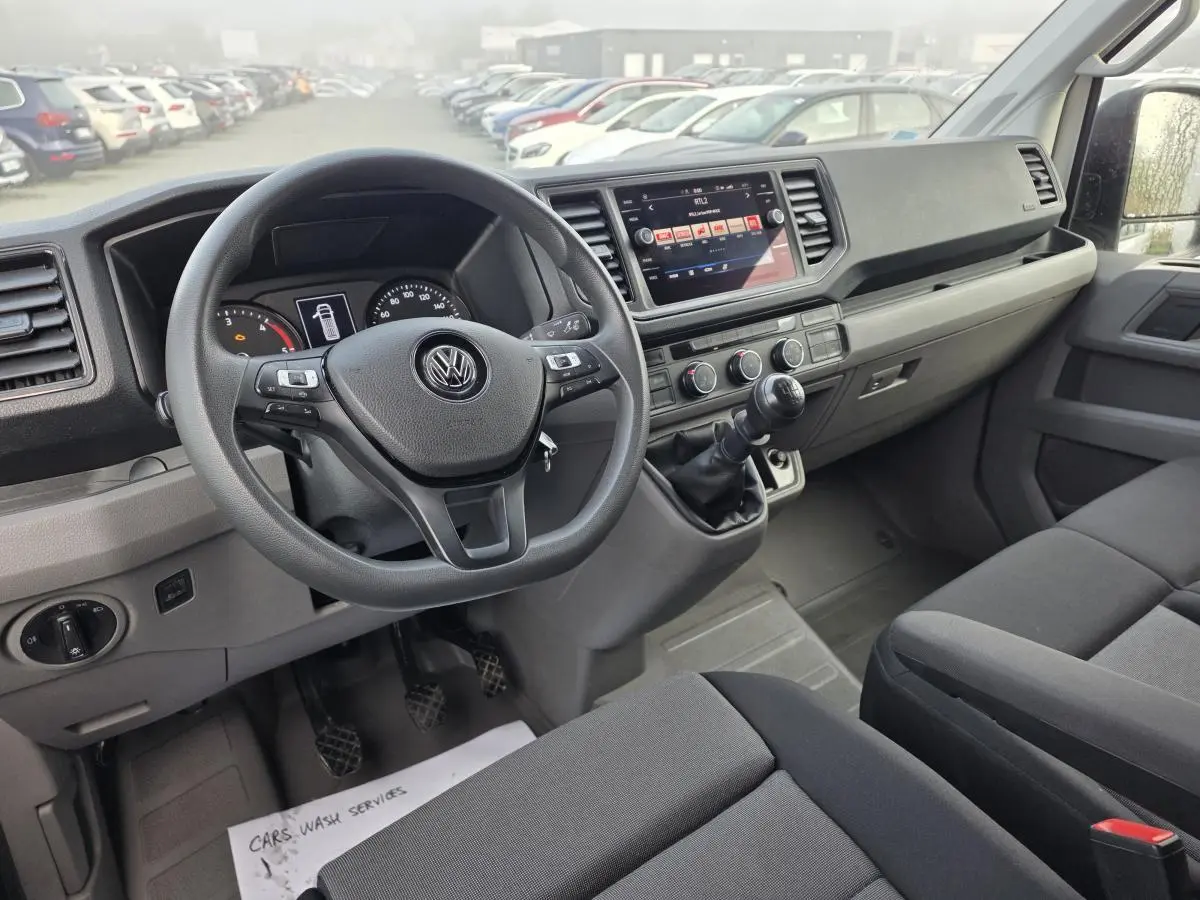 Intérieur avant du Volkswagen Crafter blanc 2023, tableau de bord noir avec volant multifonctions et boîte manuelle.