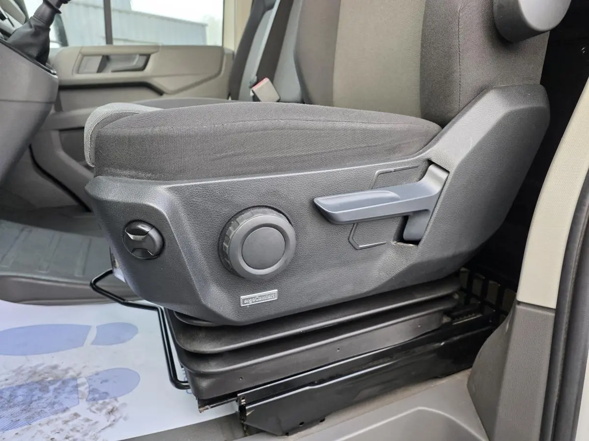 Gros plan sur le siège conducteur gris foncé avec réglages manuels dans un Volkswagen Crafter Fourgon blanc 2023.