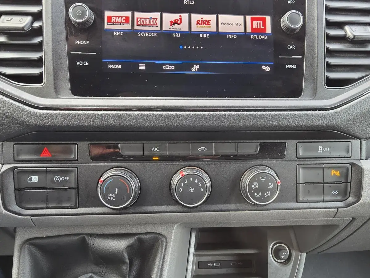 Tableau de bord et console centrale du Volkswagen Crafter blanc 2023, avec écran tactile et commandes climatisation visibles.