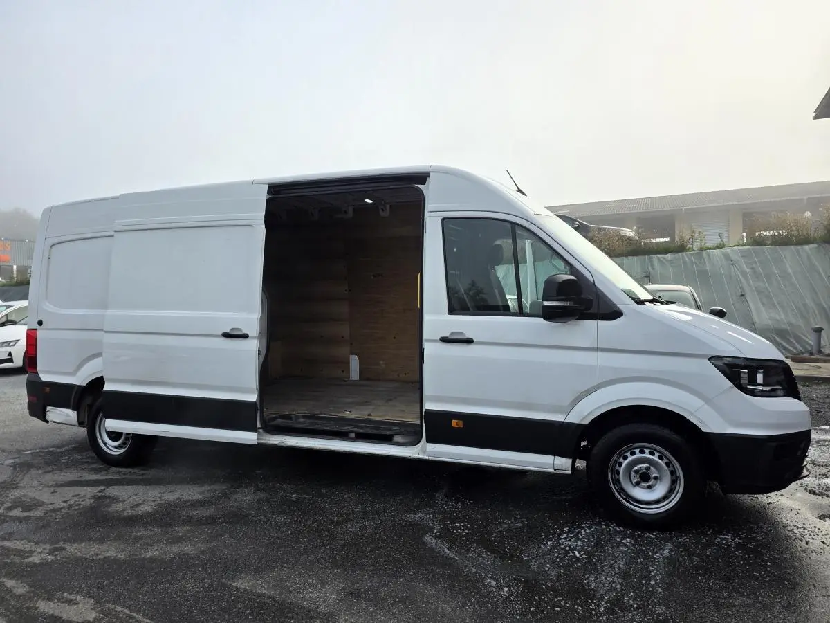 Volkswagen Crafter blanc vue de profil droit avec porte coulissante ouverte montrant l'intérieur en bois.