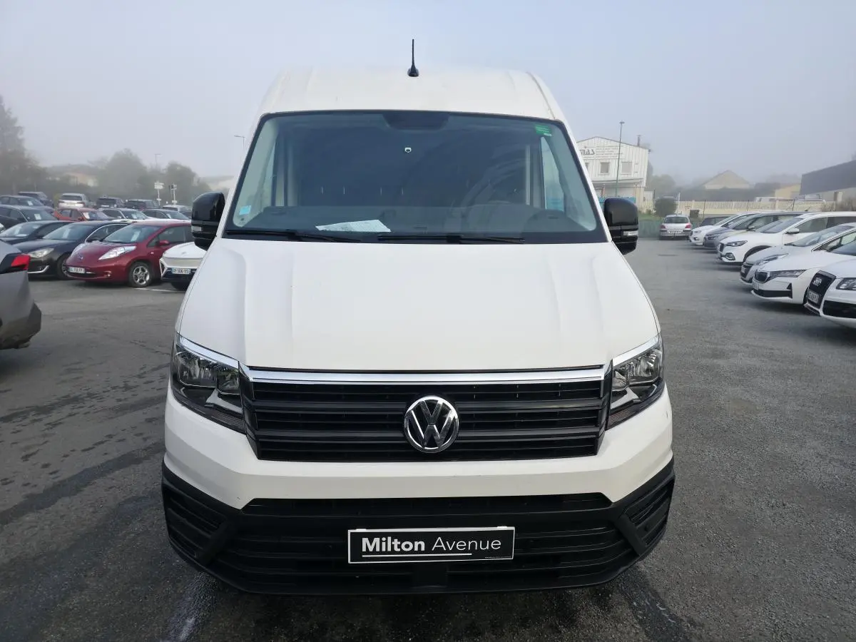 Vue avant d'un Volkswagen Crafter fourgon blanc avec calandre noire et plaque Milton Avenue visible.