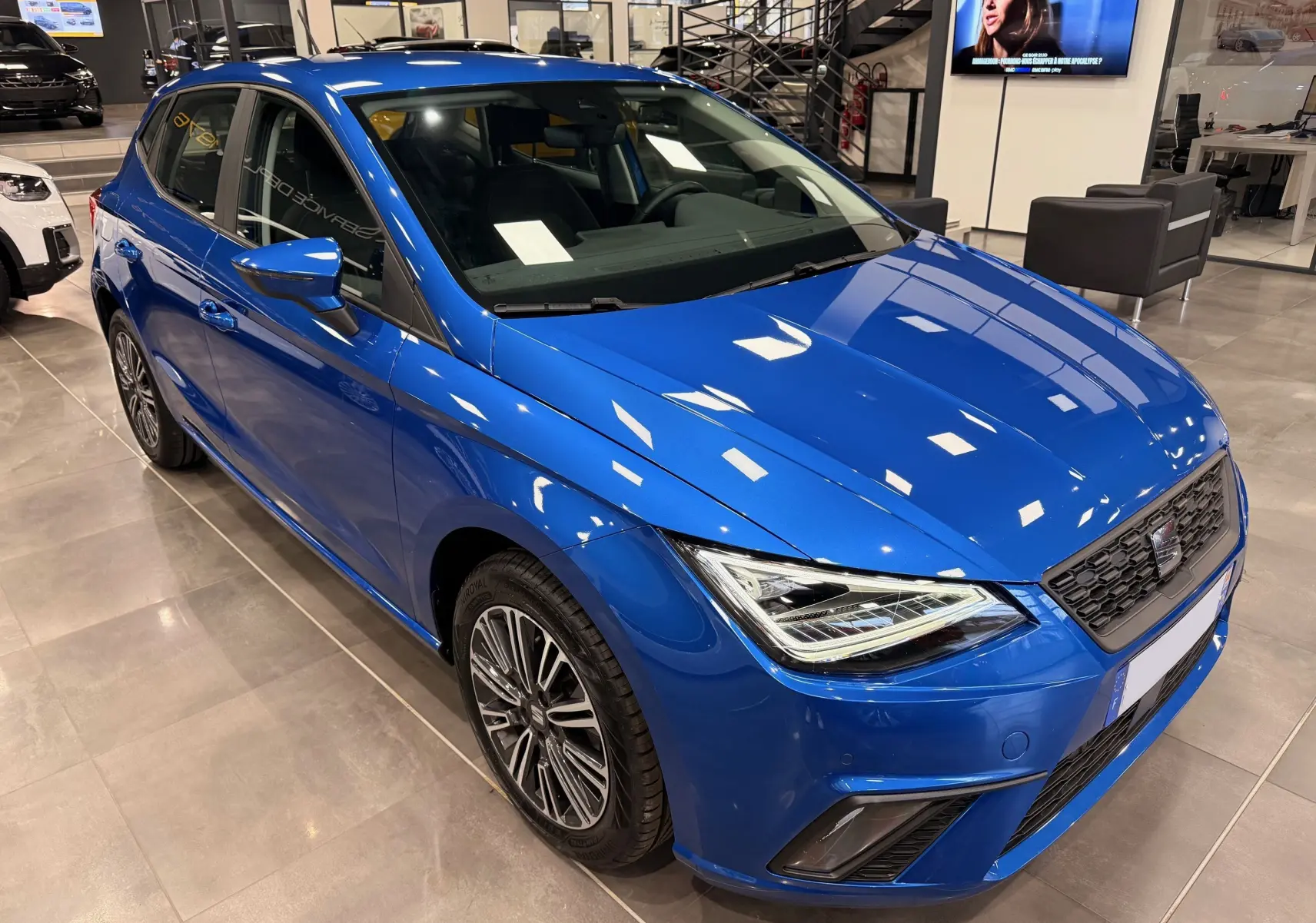 SEAT Ibiza 1.0 TSI 95CH Copa bleu vue 3/4 avant droit, avec phares LED et jantes alliage en showroom.