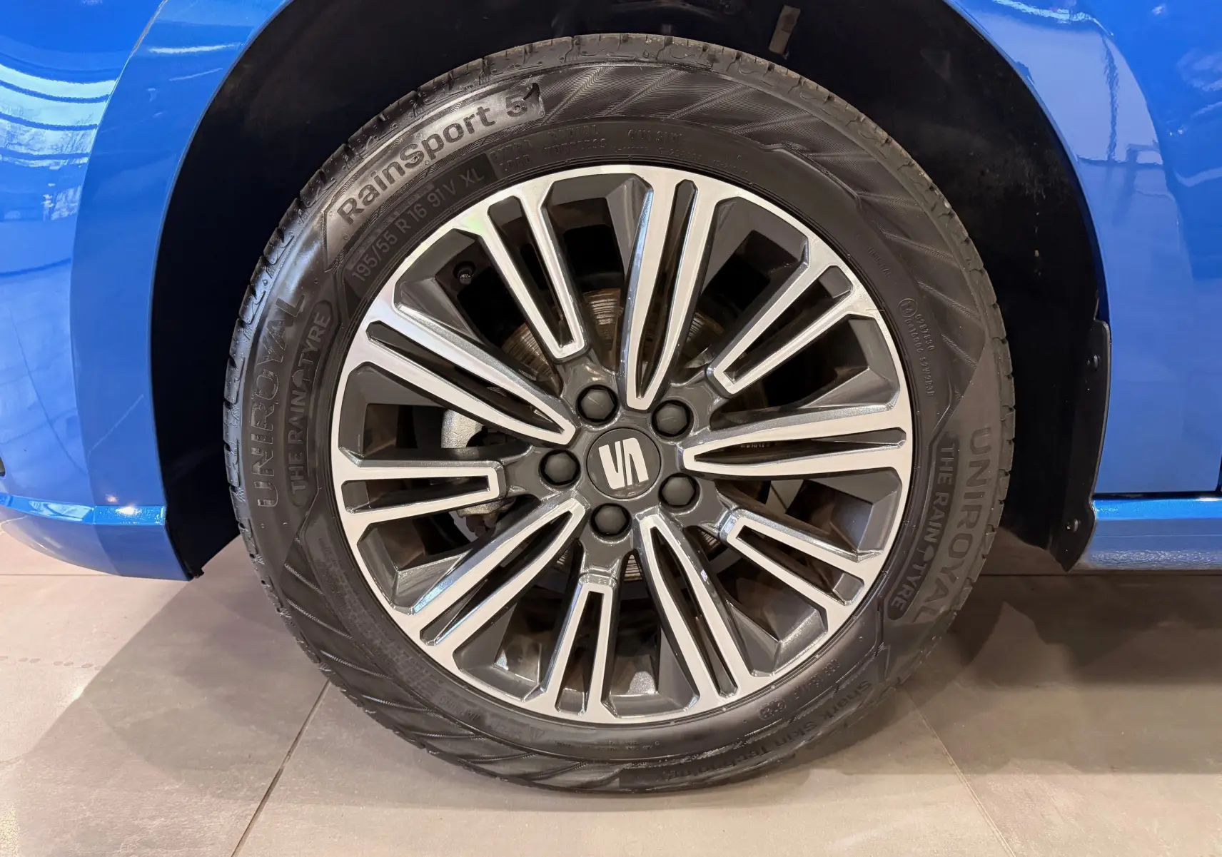 Gros plan sur la roue avant droite d'une SEAT Ibiza 2025 bleu, avec jante alliage multi-branches et pneu Uniroyal.