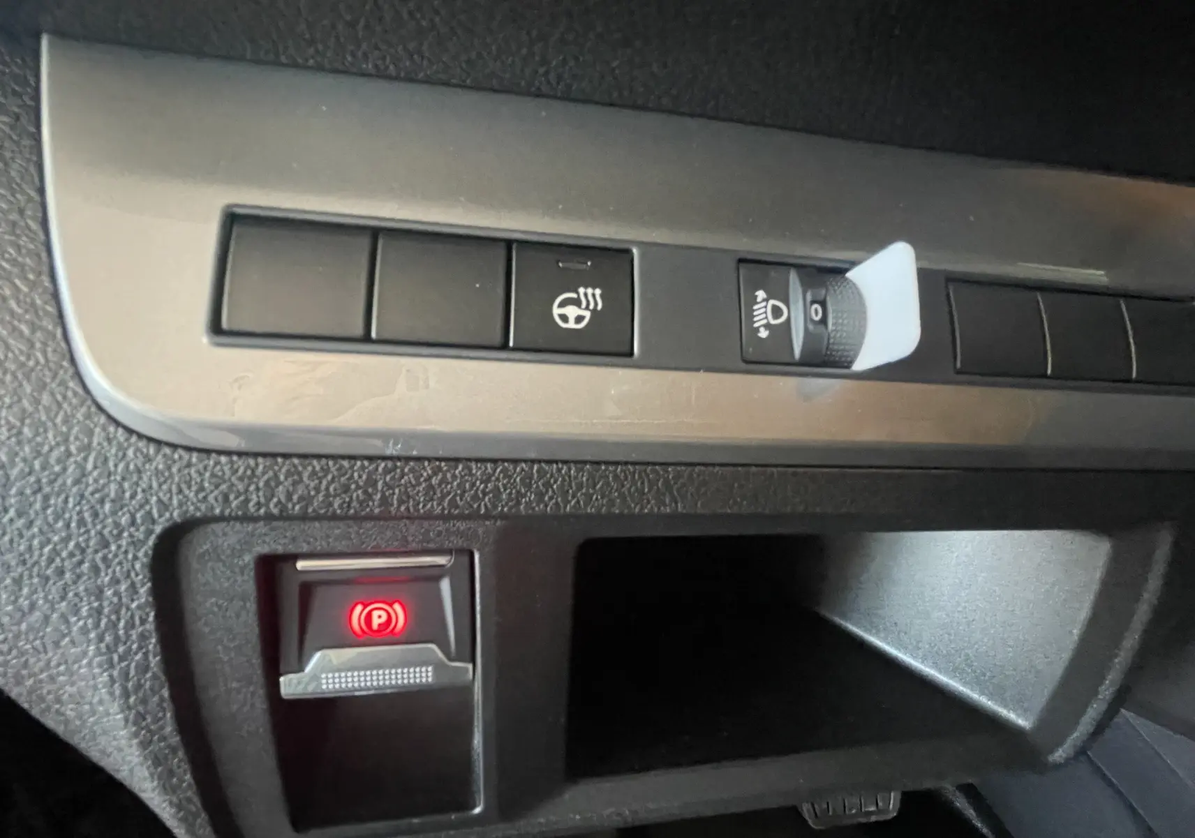 Gros plan sur les commandes du tableau de bord du Peugeot Traveller noir, avec bouton de frein à main électronique allumé.