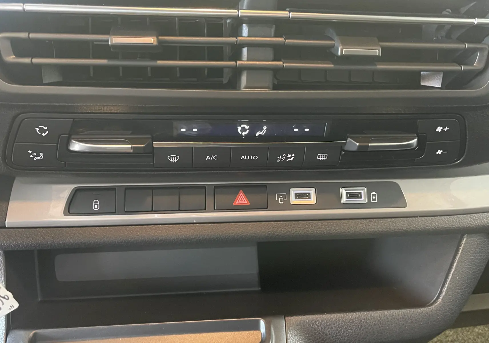 Détail de la console centrale du Peugeot Traveller 2026 noir, montrant les commandes de climatisation et ports USB.