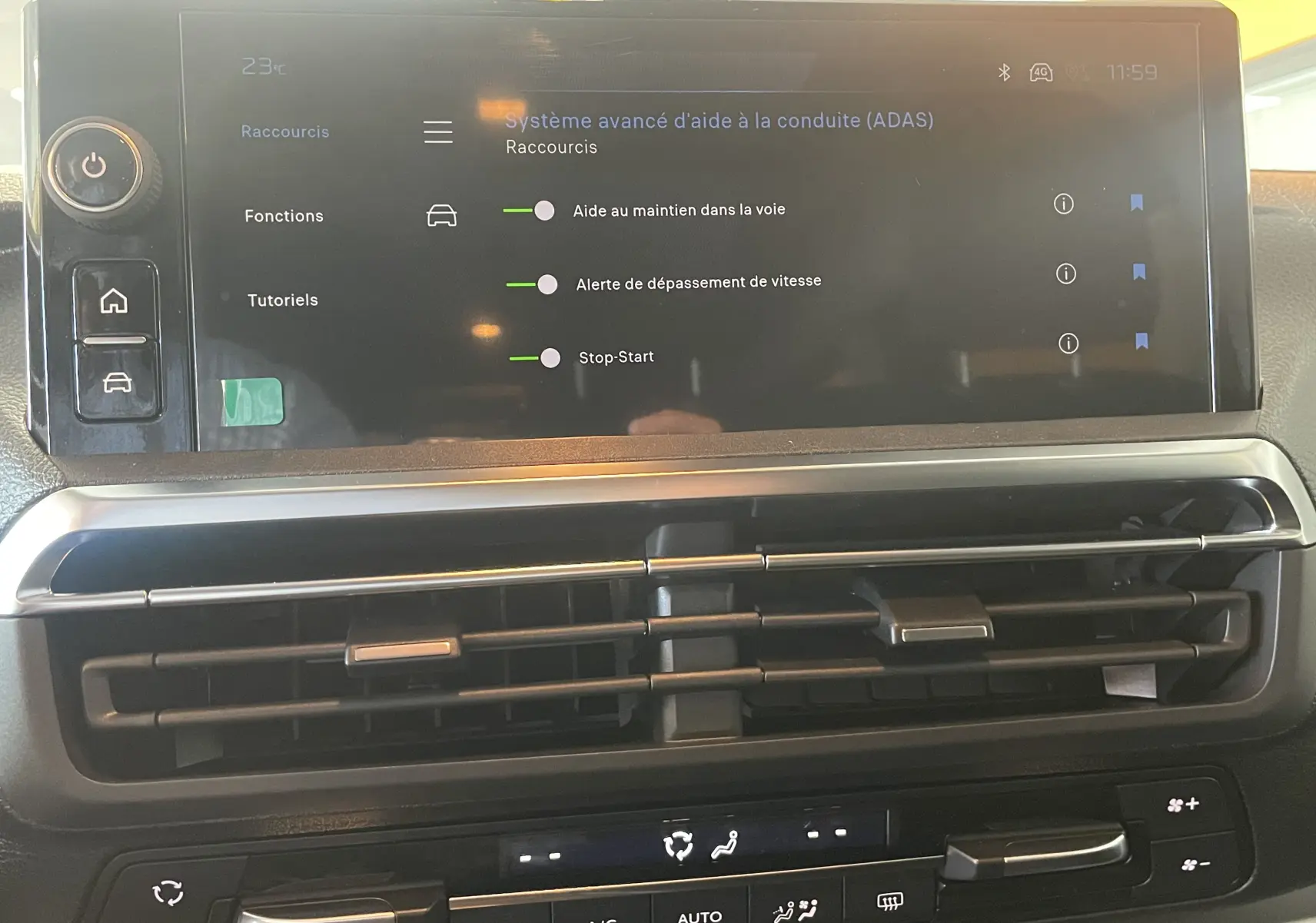 Écran tactile central du Peugeot Traveller 2026 affichant les aides à la conduite, avec les aérateurs et commandes de climatisation en dessous.