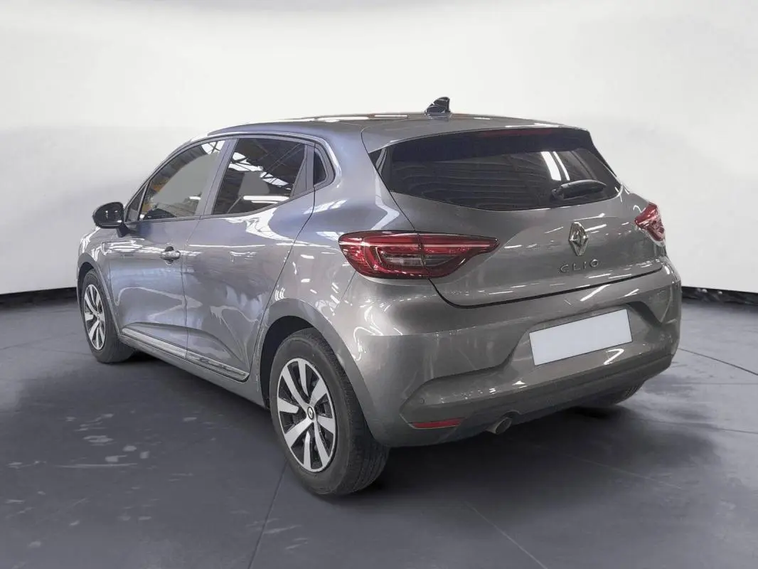 Vue 3/4 arrière gauche d'une Renault Clio gris clair 2023 avec jantes alliage 16 pouces et vitres teintées.
