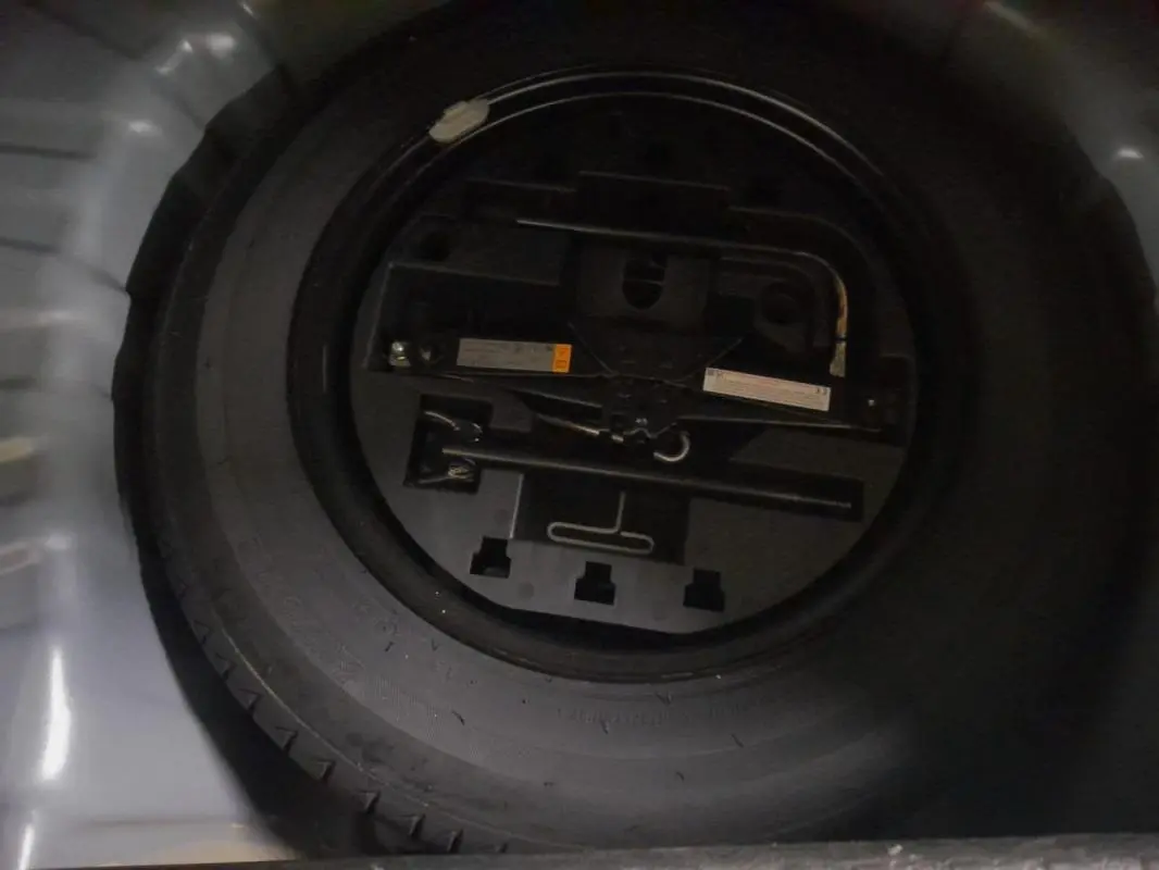 Gros plan sur la roue de secours noire dans le coffre d'une Renault Clio gris clair V TCe 90 Evolution 2023.