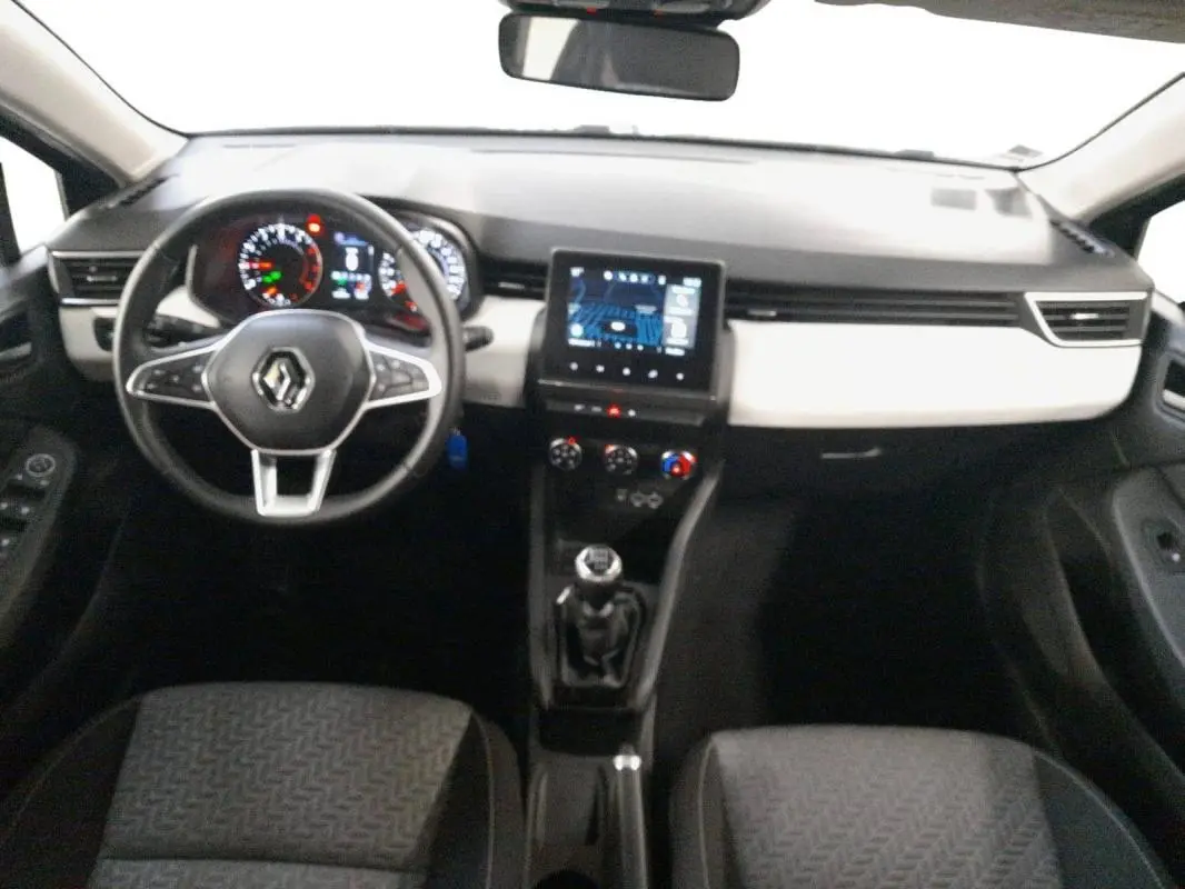 Vue intérieure avant de la Renault Clio 2023 gris clair, avec tableau de bord moderne et boîte manuelle visible.