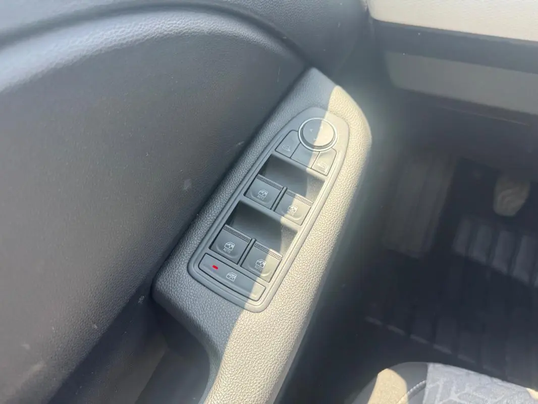 Gros plan sur les commandes des vitres électriques côté conducteur de la Renault Clio gris clair 2023.