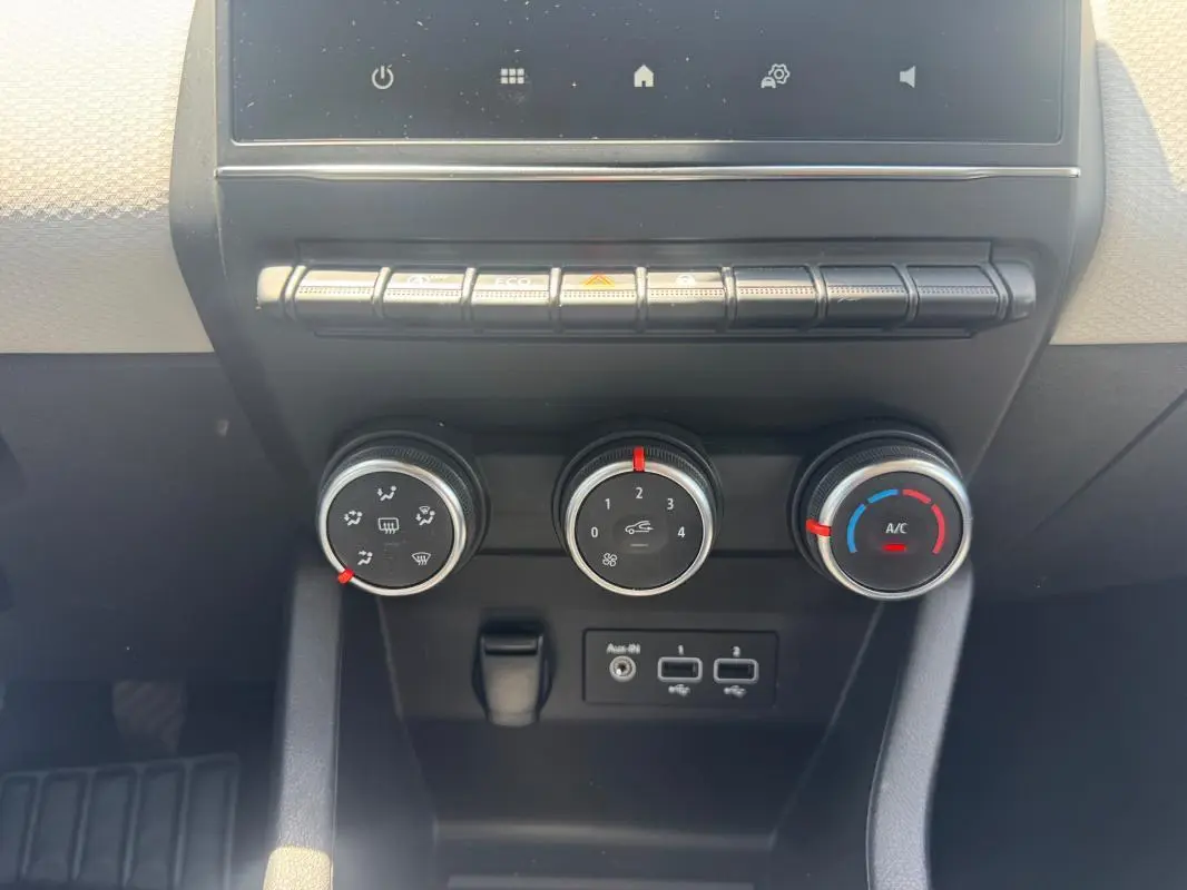 Vue rapprochée du tableau de bord de la Renault Clio V TCe 90 Evolution 2023, montrant les commandes de climatisation et ports USB.