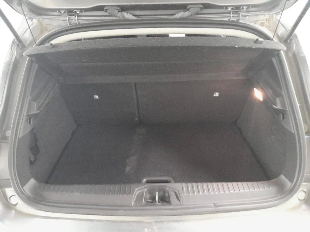Coffre ouvert vu de l'arrière d'une Renault Clio gris clair 2023, montrant l'espace de chargement vide.