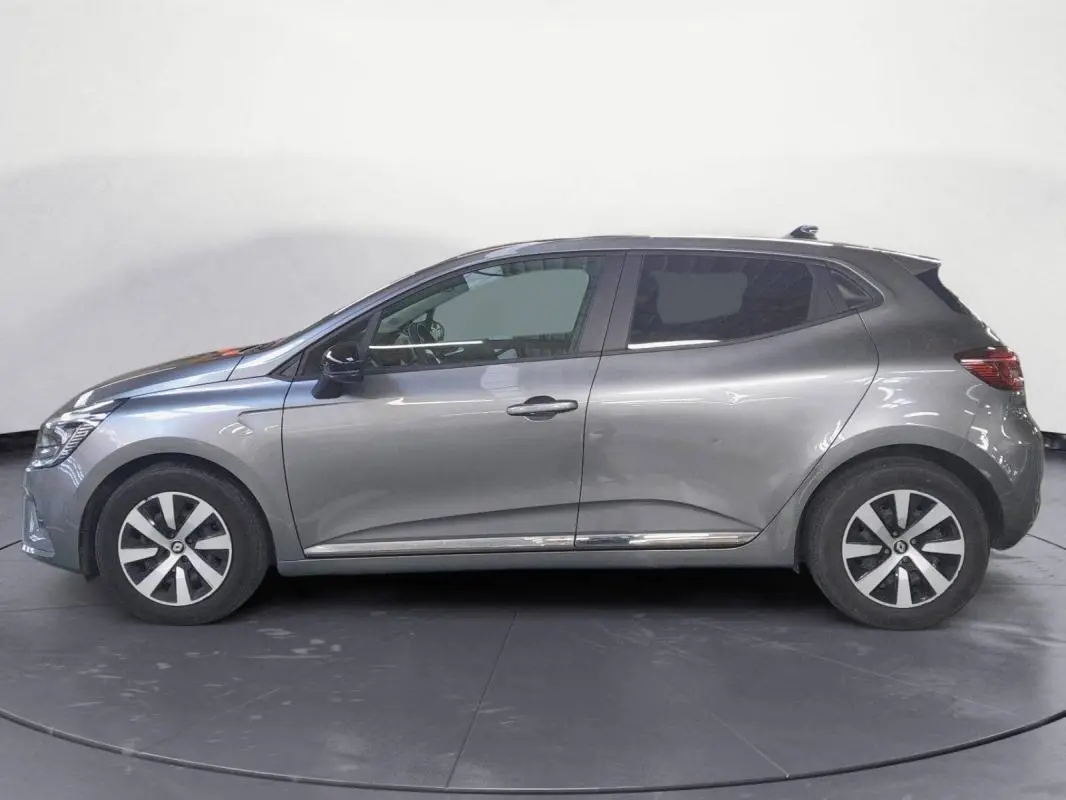 Profil côté gauche d'une Renault Clio 2023 gris clair avec jantes alliage 16 pouces et roue de secours visible.