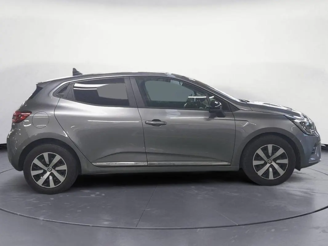 Vue de profil côté gauche d'une Renault Clio gris clair 2023 avec jantes alliage 16 pouces et roue de secours visible.