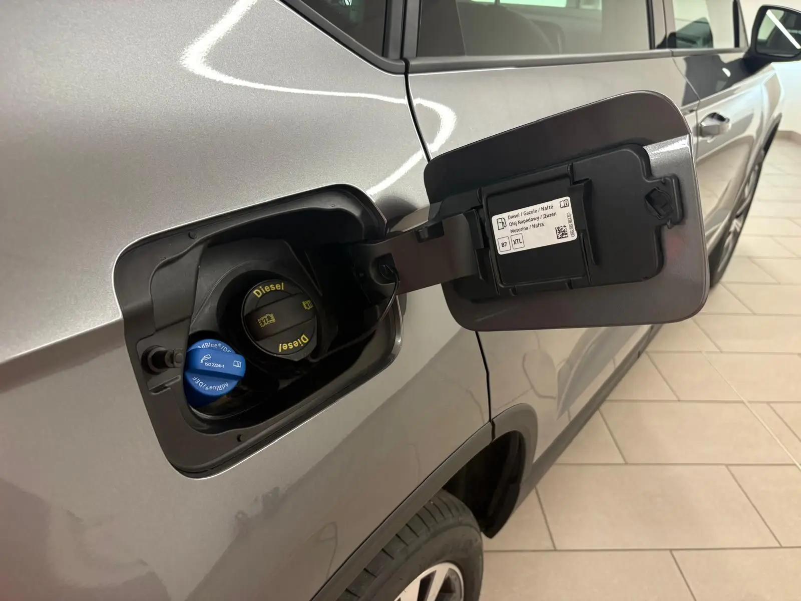 Gros plan sur la trappe à carburant ouverte côté gauche d’un SEAT Ateca gris graphite avec bouchons Diesel et AdBlue visibles.