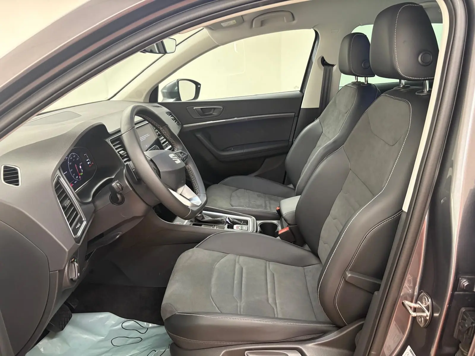 Vue intérieure côté conducteur du SEAT Ateca 2025 avec sièges en cuir et alcantara gris, tableau de bord moderne.