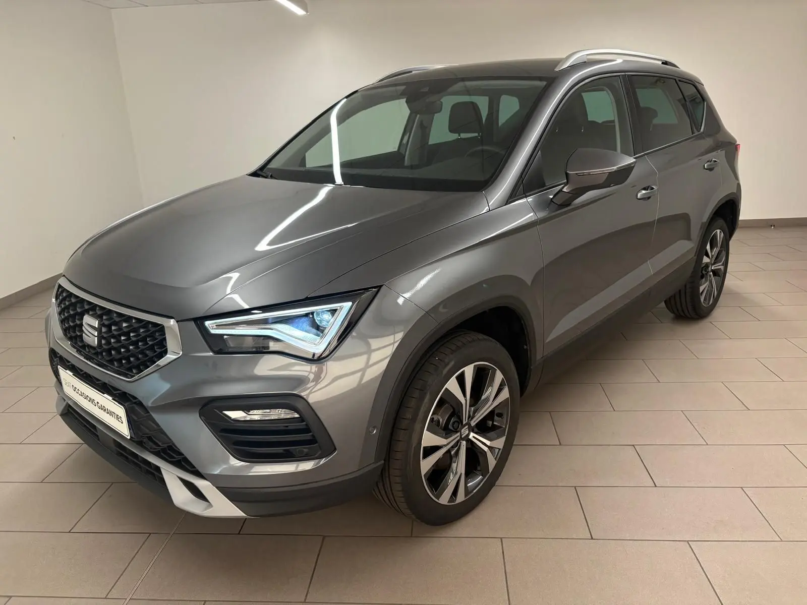 Vue 3/4 avant droit du SEAT Ateca 2025 gris graphite avec jantes alliage 18 pouces et hayon électrique mains-libres.