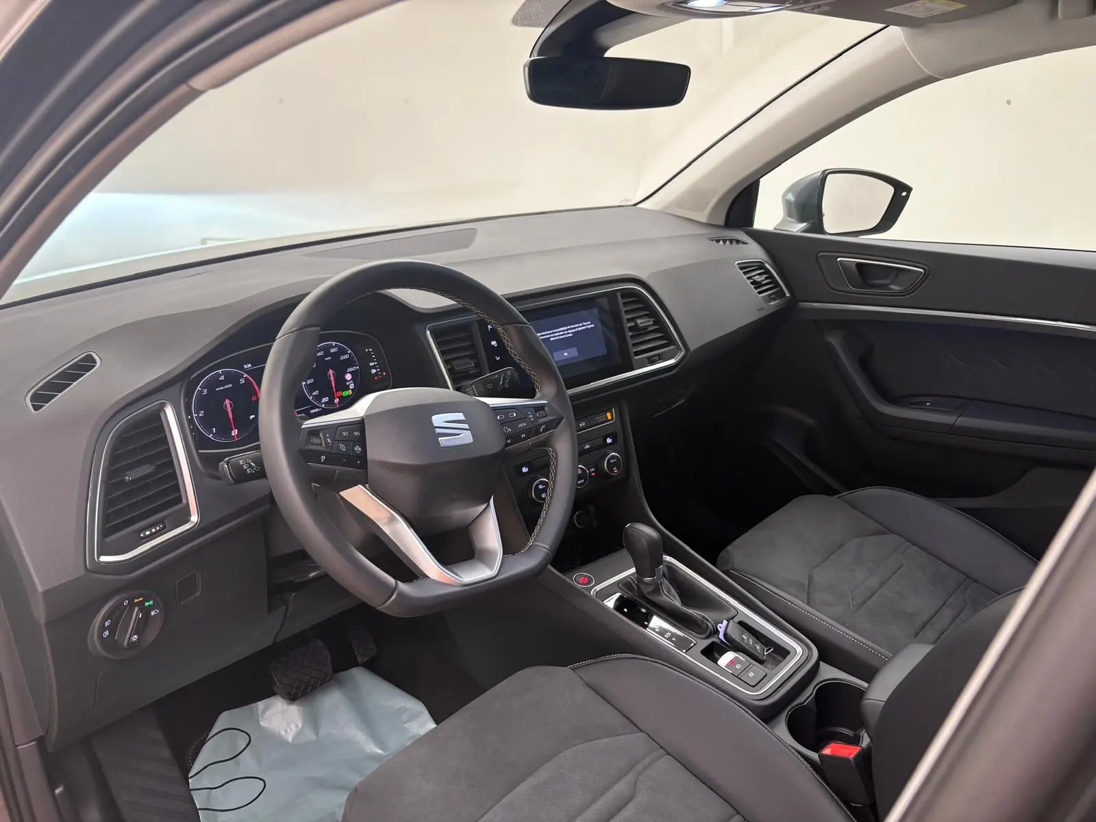 Vue intérieure côté conducteur du SEAT Ateca 2025 avec tableau de bord noir et volant multifonction.