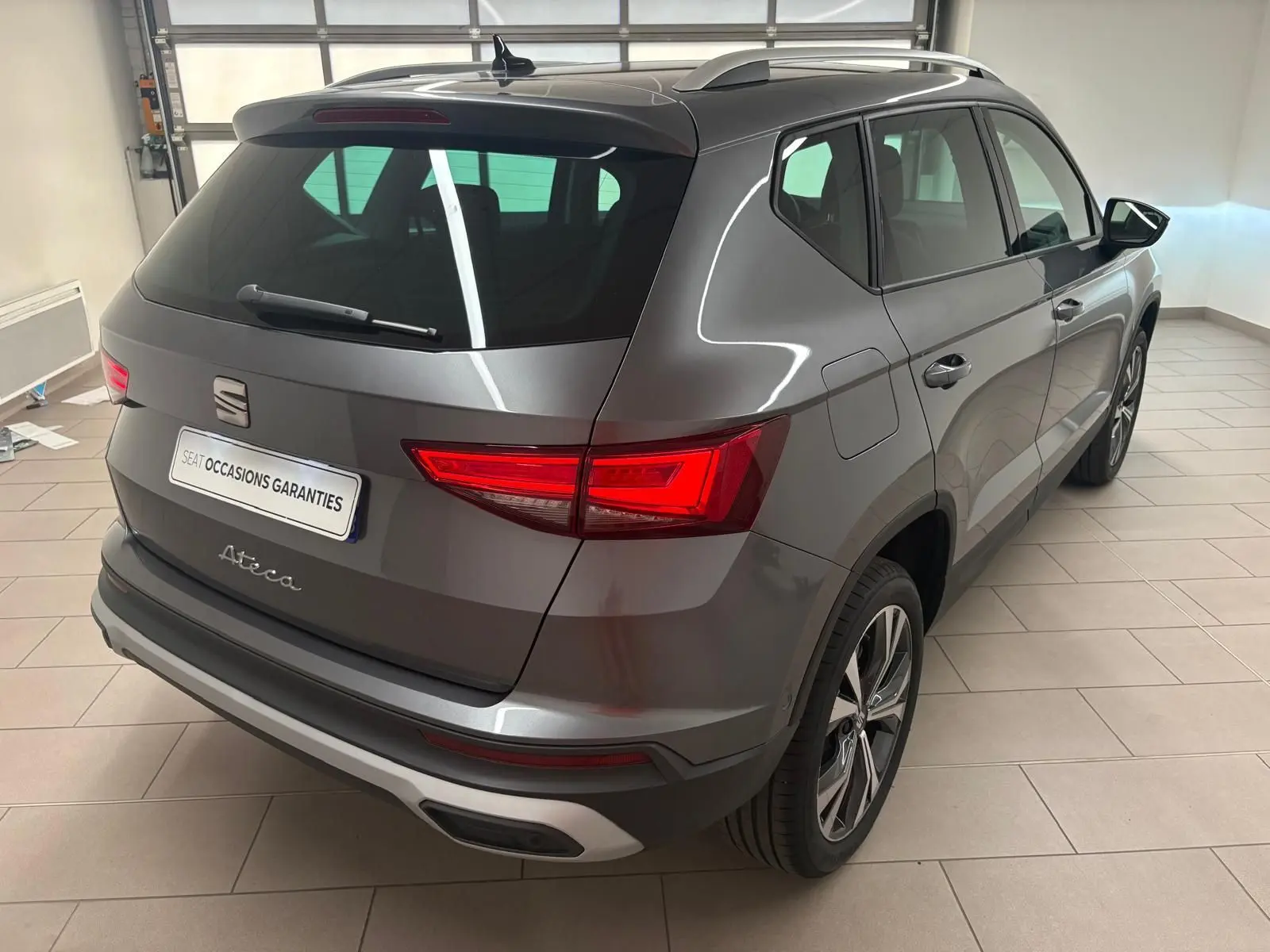 Vue 3/4 arrière droite du SEAT Ateca gris graphite 2025 avec jantes alliage 18'' et hayon électrique mains-libres.