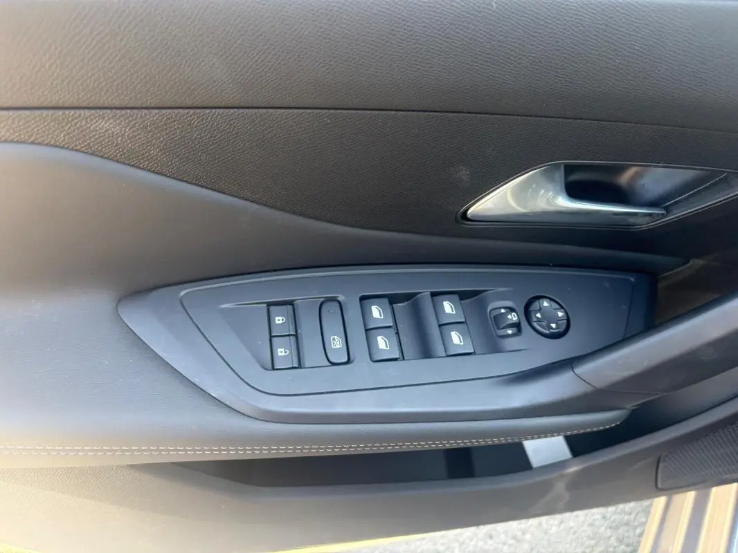Gros plan sur la commande des vitres et rétroviseurs côté gauche de la porte intérieure d’une Peugeot 308 PHEV 180 e-EAT8 Allure gris clair 2024.