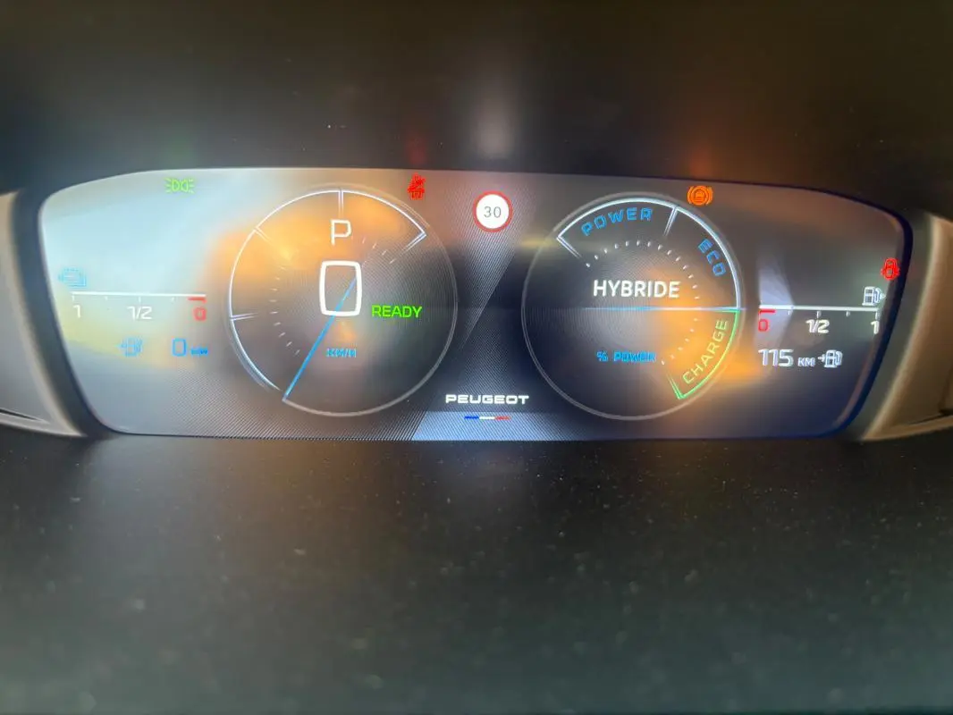 Tableau de bord numérique du Peugeot 308 PHEV 2024 affichant mode hybride, vitesse à zéro et autonomie électrique de 115 km.