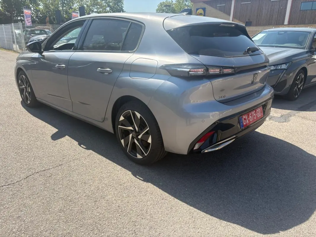 PEUGEOT 308 PHEV 180 e-EAT8 Allure gris clair vue 3/4 arrière droit avec jantes noires et détails noirs brillants.