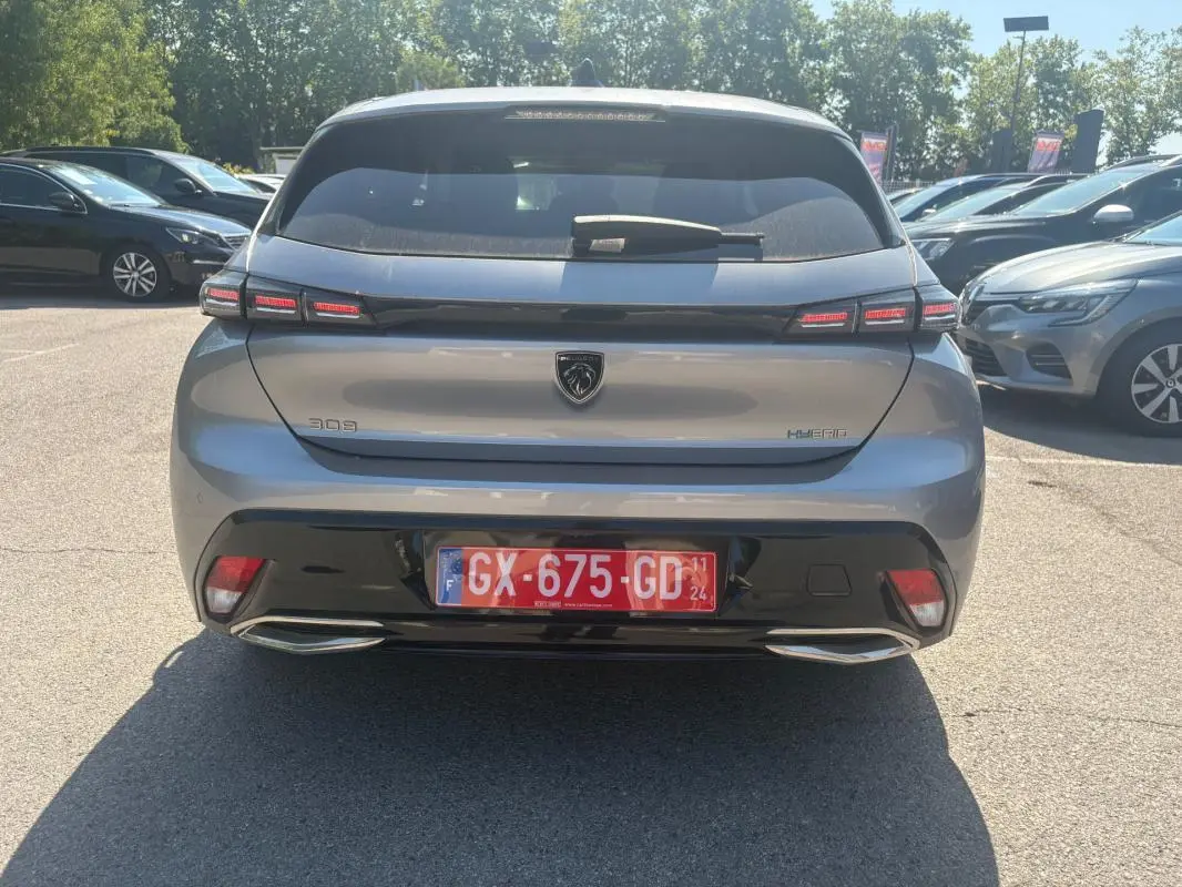 Vue arrière d’une Peugeot 308 PHEV 180 e-EAT8 Allure gris clair 2024 avec feux LED et double sortie d’échappement intégrée.