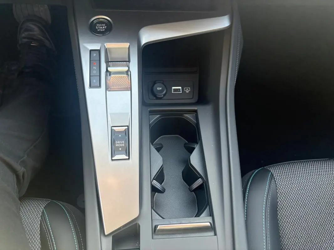 Vue plongeante sur la console centrale de la Peugeot 308 PHEV 180 e-EAT8 Allure 2024, avec levier de vitesses et porte-gobelets.